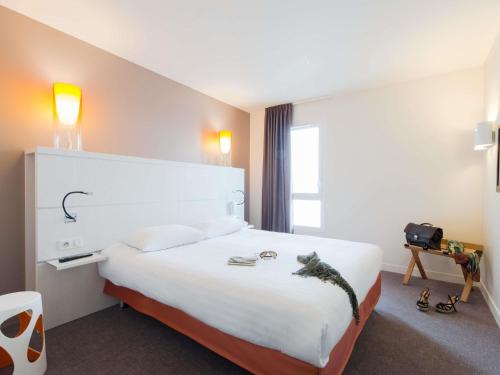 a hotel room with a large white bed in it at Hôtel Confort La Rochelle Centre les Minimes in La Rochelle