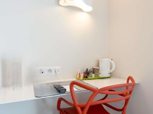 a red chair sits at a counter in a kitchen at Hôtel Confort La Rochelle Centre les Minimes in La Rochelle
