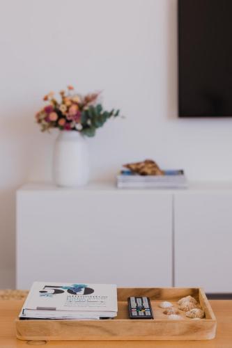 a table with a book and a vase with flowers at Marea Alta in La Caleta