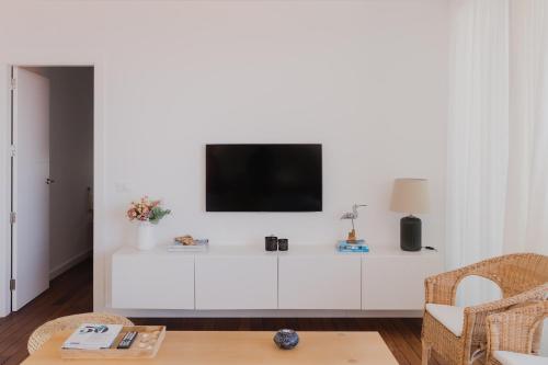 Una sala de estar con un televisor en una pared blanca. en Marea Alta, en La Caleta