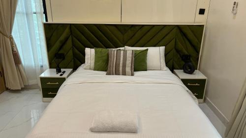a bedroom with a large bed with a green headboard at Nimbus Nook Apartments, GRA Ikeja, Lagos in Ikeja