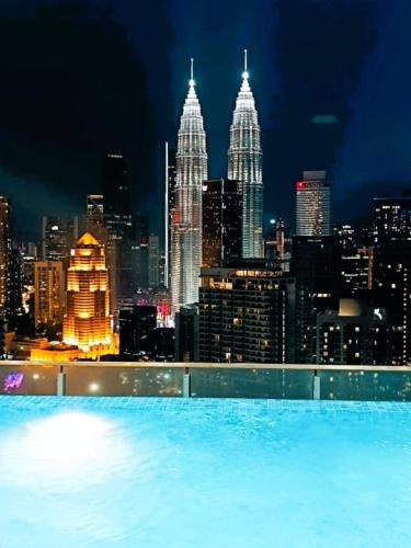 a pool with a view of the city at night at The Luxe & Colony Infinitum KLCC by CoupleStay in Kuala Lumpur