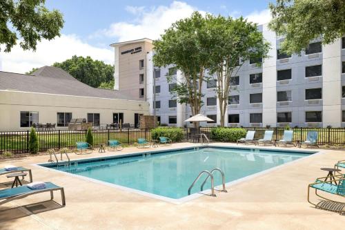 a swimming pool with chairs and a building at TownePlace Suites by Marriott Charlotte LoSo Airport in Charlotte
