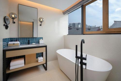 Un baño con bañera, lavabo y espejo. en Four Points by Sheraton Xi'an Dayan Pagoda, en Xi'an