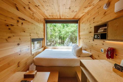 a bedroom in a wooden cabin with a bed and a window at Postcard Cabins Wild Rose, Outdoor Collection by Marriott Bonvoy in Wild Rose