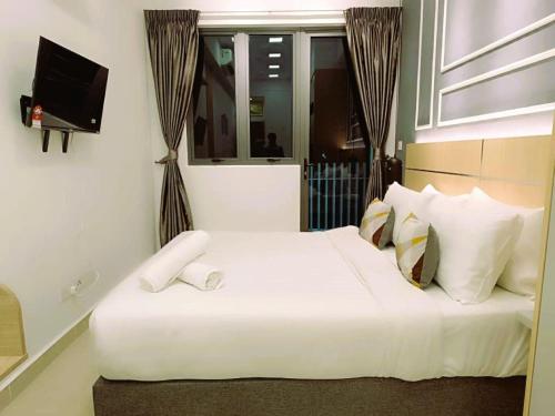 a bedroom with a white bed with a window and a television at The Luxe & Colony Infinitum KLCC by CoupleStay in Kuala Lumpur