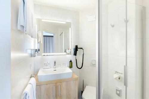 a white bathroom with a sink and a shower at Four Points Flex by Sheraton Salzburg Messe in Salzburg