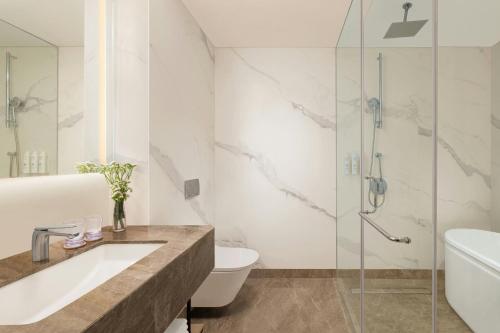 a bathroom with a shower and a sink and a toilet at Marriott Executive Apartments Bengaluru UB City in Bengaluru