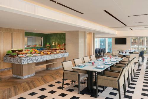a restaurant with long tables and chairs and a bar at Marriott Executive Apartments Bengaluru UB City in Bengaluru