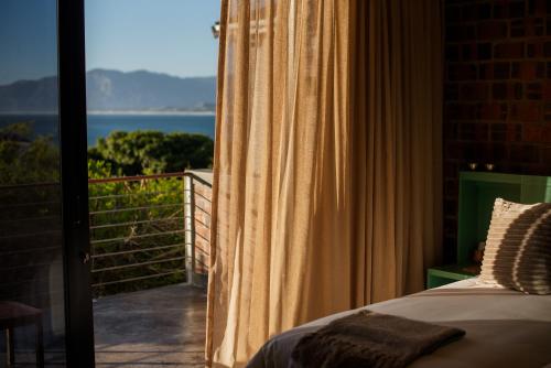 a bedroom with a bed and a view of the ocean at Whalesong Lodge in Gansbaai