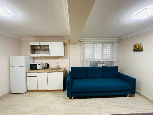 a living room with a blue couch and a kitchen at Бюджетна студія біля резиденції університету in Chernivtsi