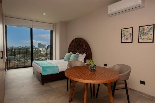 グアダラハラにあるDepartamento con cama queen, alberca, gimnasio y coworking, a minutos de Expo Guadalajaraのベッドとテーブルと窓のある寝室