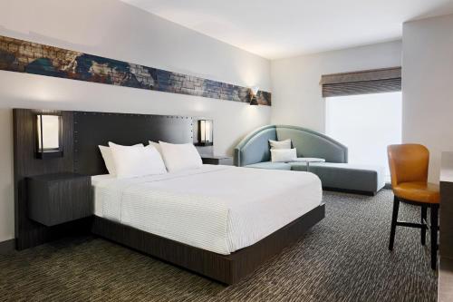 a hotel room with a large bed and a chair at The Elmore Hotel, DFW Southlake, a Tribute Portfolio Hotel in Southlake
