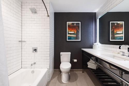 a bathroom with a tub and a toilet and a sink at The Elmore Hotel, DFW Southlake, a Tribute Portfolio Hotel in Southlake