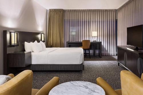a hotel room with a bed and a flat screen tv at The Elmore Hotel, DFW Southlake, a Tribute Portfolio Hotel in Southlake