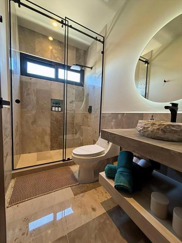 a bathroom with a toilet and a glass shower at Beachfront 2BR 2BA Condo w Balcony, Ocean Views in Puerto Morelos