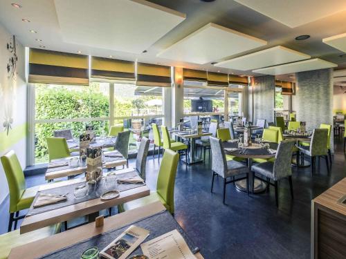 a restaurant with wooden tables and green chairs at Mercure Annecy Sud in Annecy