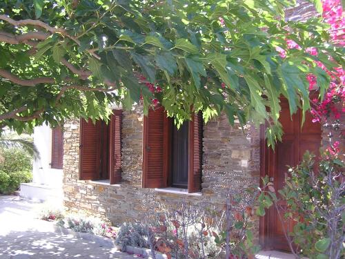 a stone building with red windows and a tree at Santamare Apartment in Agios Sostis