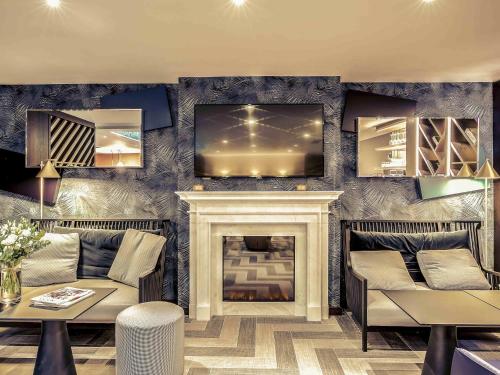 a living room with a fireplace and a tv at Mercure Paris Arc de Triomphe Etoile in Paris