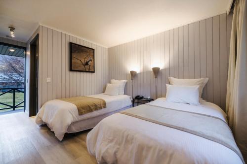 a hotel room with two beds and a window at Hotel Lago Grey in Torres del Paine