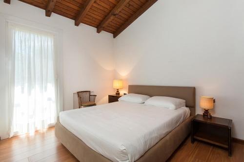 a bedroom with a large white bed with two lamps at La Motta by Impero House in Brisino