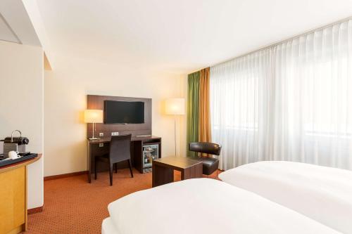 a hotel room with a bed and a desk and a television at NH Berlin City Ost in Berlin