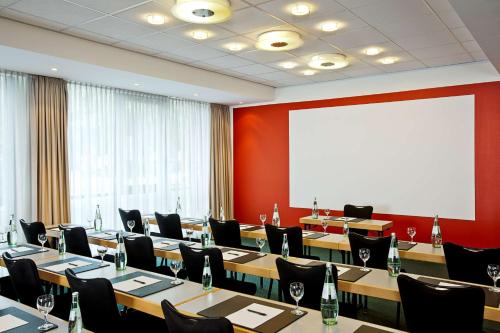 a conference room with tables and chairs and a projection screen at NH Berlin City Ost in Berlin