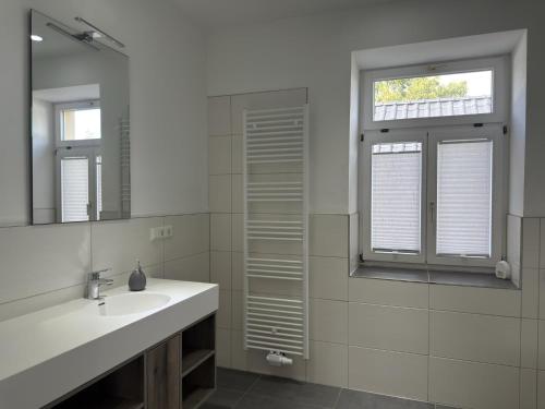 a white bathroom with a sink and a mirror at Ferienwohnung im Zentrum von Ballenstedt in Ballenstedt