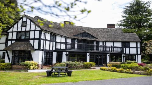 a black and white house with a picnic table in front of it at Thatchers, BW Signature Collection in East Horsley