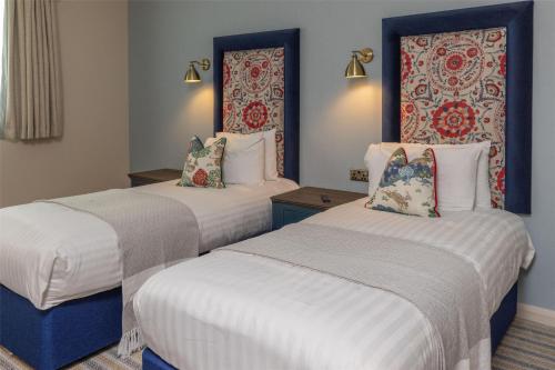two beds in a hotel room with white and blue at Thatchers, BW Signature Collection in East Horsley