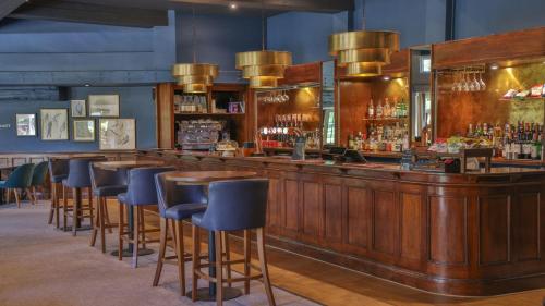 a bar with blue bar stools in a restaurant at Thatchers, BW Signature Collection in East Horsley