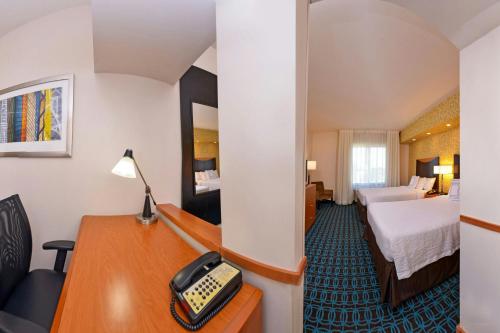 a hotel room with a bed and a desk with a phone at Fairfield Inn & Suites Santa Maria in Santa Maria