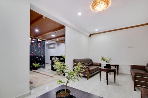 a living room with couches and a table with a plant at Capital O Elegant Amethyst Business Hotel Near Ragigudda Sri Prasanna Anjaneyaswamy Temple in Bengaluru