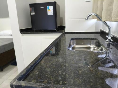 a kitchen counter with a sink and a water fountain at Xavi Studio in Bauru