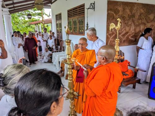 a group of people standing around a priest in a ceremony at Buddothpado International Meditation Center in Anguruwatota
