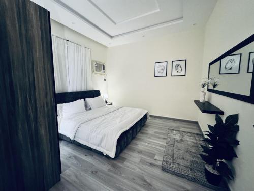 a bedroom with a bed with white sheets and wood floors at Modern Apartment 2 in Jeddah