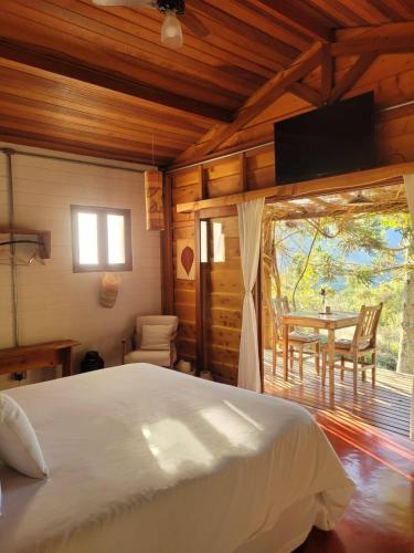 a bedroom with a bed and a table and chairs at Cabana Arbosana in São Bento do Sapucaí