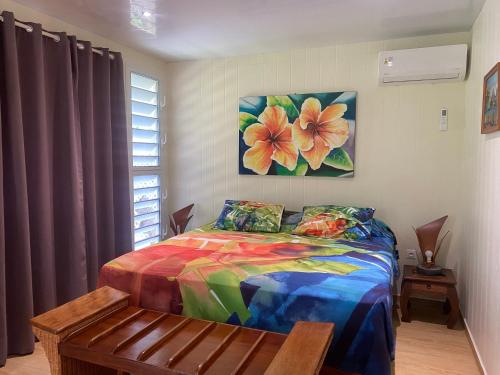 a bedroom with a colorful bed and a painting on the wall at FARE TITAINA in Hauru