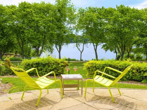 three yellow chairs and a table in a park at Novotel Paris Créteil Le Lac in Créteil