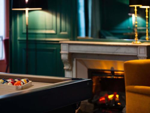 a living room with a fireplace and a table with a candle at Hotel Novotel Domaine de Maffliers - Paris Val-d'Oise in Maffliers