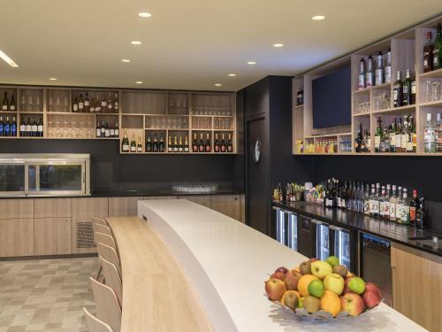 a bar with a table with a bowl of fruit on it at Novotel Paris Nord Expo Aulnay in Aulnay-sous-Bois