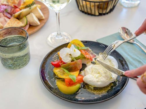 a person cutting a plate of food with a fork and knife at Mercure Aix en Provence Beaumanoir in Aix-en-Provence