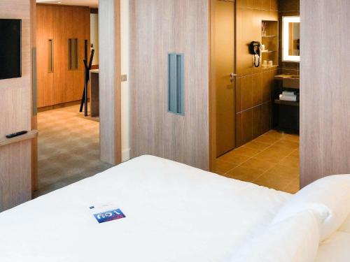 a hotel room with a bed and a bathroom at Novotel Saclay in Saclay
