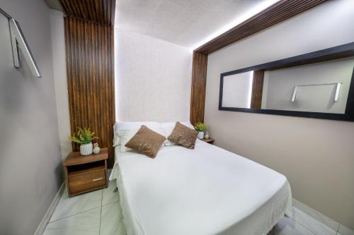a bedroom with a white bed and a mirror at 6 Habitaciones con un Jacuzzi Privado in Medellín