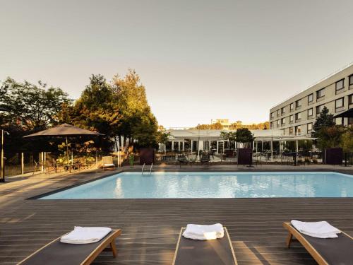a swimming pool with two chairs and a building at Novotel Nancy in Nancy