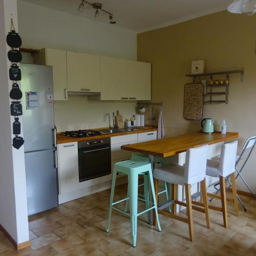 a kitchen with a wooden table and a refrigerator at Casa in collina, vista mare. in Nibbiaia