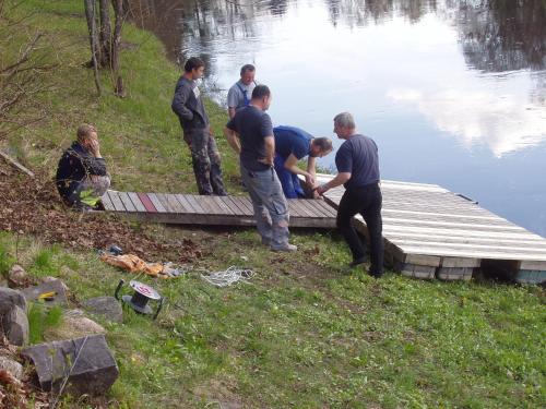 a group of men standing on a dock next to a lake at Villa River Rose in Jõesuu