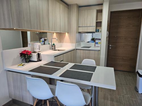 a kitchen with a white counter and white chairs at Claro Centro Temuco in Temuco