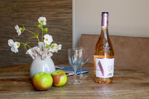 a bottle of wine and two apples on a wooden table at Het Moleneind - Studio en Vakantiehuis in Kapel-Avezaath