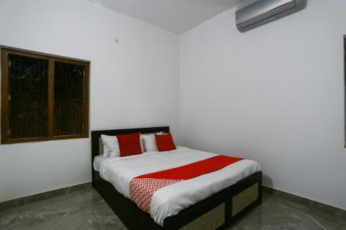 a white room with a bed with red pillows at Hotel O Al Ameen Residency in Kannur